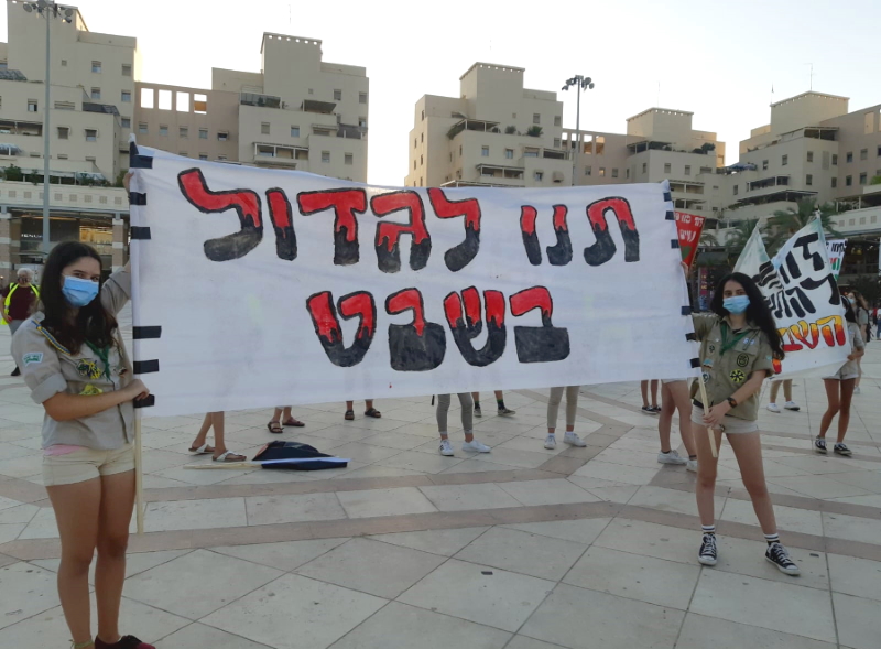 נערות מחזיקות שלט עם הכיתוב תנו לגדול בשבט