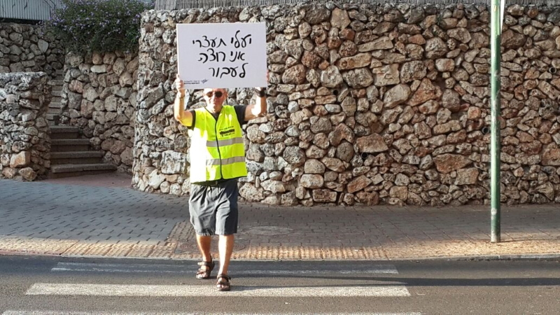 מעביר דרך המחזיק שלט עם הכיתוב יעלי תעצרי אני רוצה לעבור